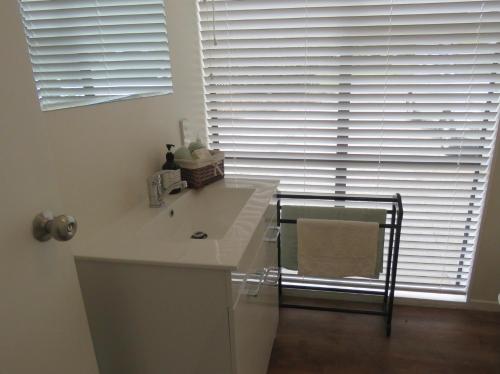 een badkamer met een wastafel en een raam met jaloezieën bij Rotorua Tranquility in Rotorua