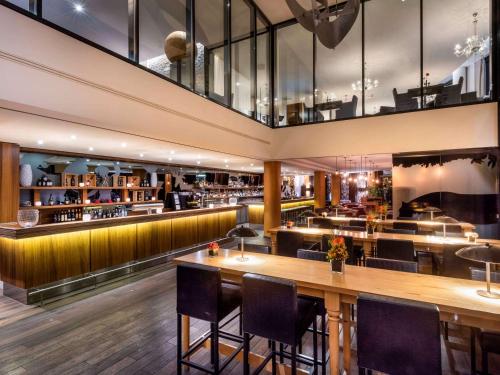 a restaurant with a bar with tables and chairs at Mövenpick Hotel Stuttgart Airport in Stuttgart