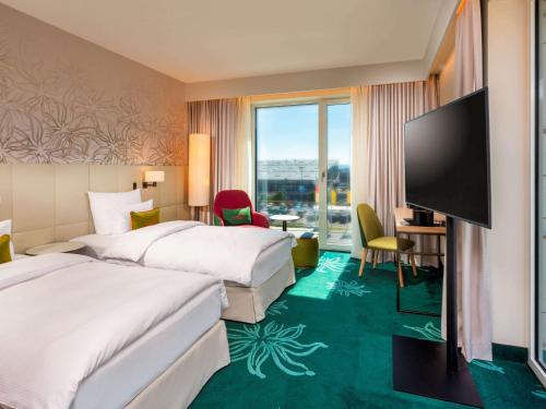 um quarto de hotel com duas camas e uma televisão de ecrã plano em Mövenpick Hotel Stuttgart Messe & Congress em Stuttgart