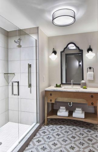 a bathroom with a shower and a sink and a mirror at The Hamilton Alpharetta, Curio Collection By Hilton in Alpharetta
