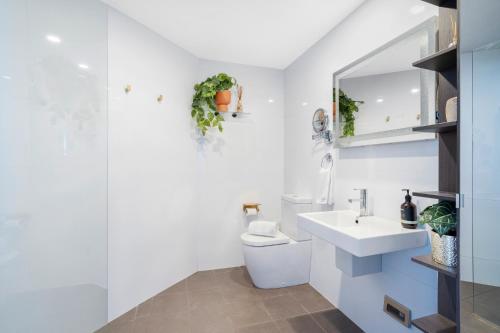 a white bathroom with a toilet and a sink at 603 Newcastle Beachfront Apartment in Newcastle