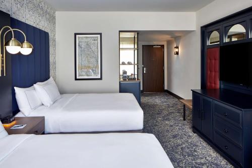 a hotel room with two beds and a flat screen tv at The Hamilton Alpharetta, Curio Collection By Hilton in Alpharetta