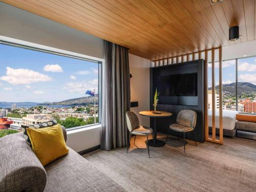 a bedroom with a bed and a large window at Mövenpick Hotel Hobart in Hobart