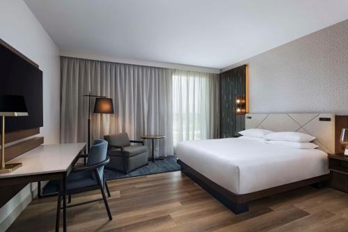 a hotel room with a large bed and a desk and a desk at Hyatt Regency Baytown-Houston in Baytown