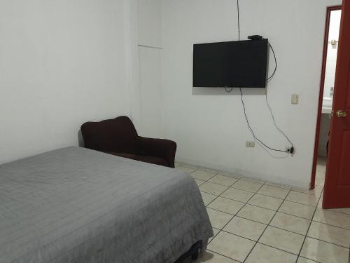 um quarto com uma cama e uma televisão na parede em Hotel Bluehouse em Guatemala