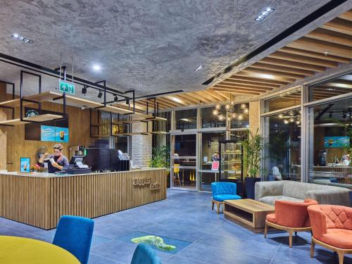 a lobby with a bar with blue chairs and tables at Ibis Istanbul Airport in Istanbul