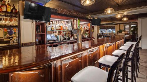 a bar with a wooden counter and chairs in a room at The Hub Murray Hill, BW Premier Collection in New Providence