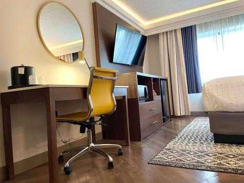 a hotel room with a desk and a yellow chair at The Hub Murray Hill, BW Premier Collection in New Providence