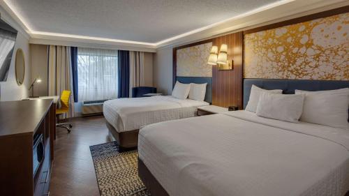 a hotel room with two beds and a television at The Hub Murray Hill, BW Premier Collection in New Providence
