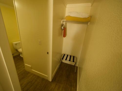 Habitación pequeña con baño con aseo y pasillo. en Creston Valley Motel, en Creston
