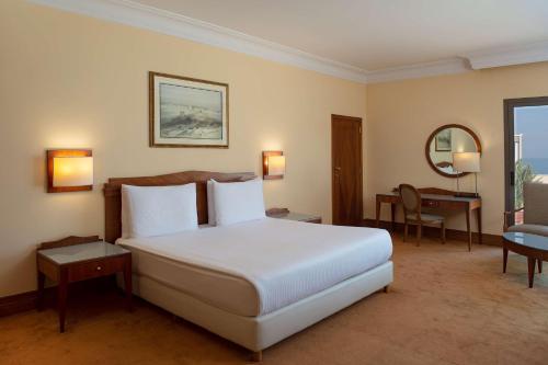 a bedroom with a large white bed and a desk at Radisson Blu Martinez Beirut in Beirut