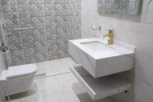 a white bathroom with a sink and a toilet at شقق بيت المدينة للشقق المخدومة in Qabāʼ