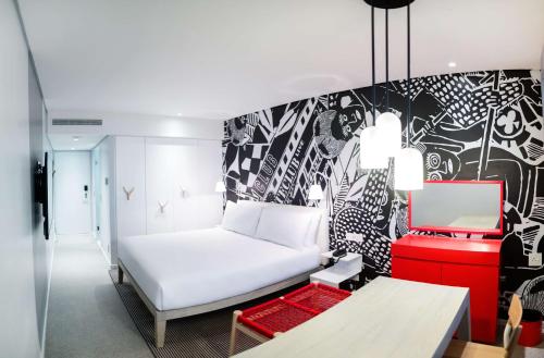 a bedroom with a white bed and a black and white wall at Radisson RED Hotel V&A Waterfront Cape Town in Cape Town