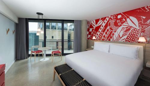 a hotel room with a bed and a table with a view at Radisson RED Hotel V&A Waterfront Cape Town in Cape Town