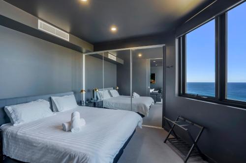 two beds in a room with a view of the ocean at 703 Luxury Ocean View Apartment in Newcastle
