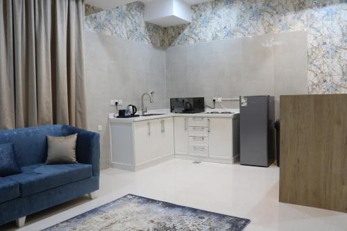 a living room with a blue couch and a kitchen at شقق بيت المدينة للشقق المخدومة in Al Madinah
