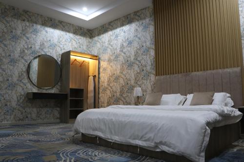 a bedroom with a large bed and a mirror at شقق بيت المدينة للشقق المخدومة in Al Madinah