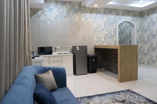 a living room with a blue couch and a kitchen at شقق بيت المدينة للشقق المخدومة in Al Madinah