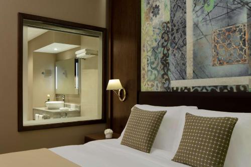 a bedroom with a bed with a mirror and a sink at Radisson Blu Hotel & Resort, Sohar in Sohar