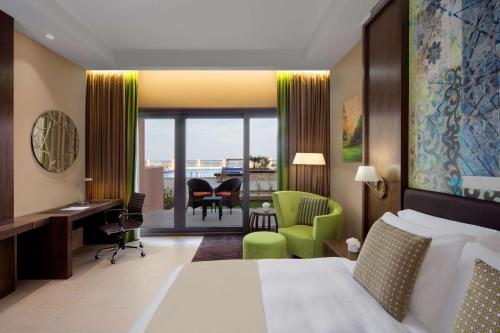 a hotel room with a bed and a desk and a chair at Radisson Blu Hotel & Resort, Sohar in Sohar