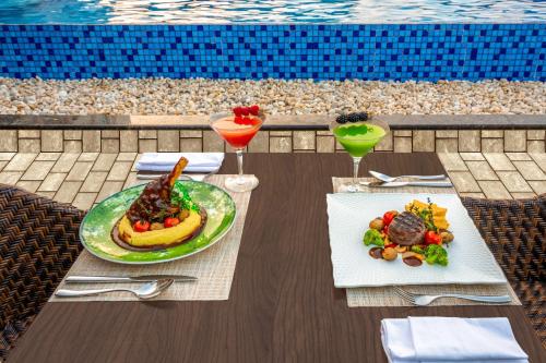a table with two plates of food next to a pool at Radisson Blu Hotel & Resort, Sohar in Sohar