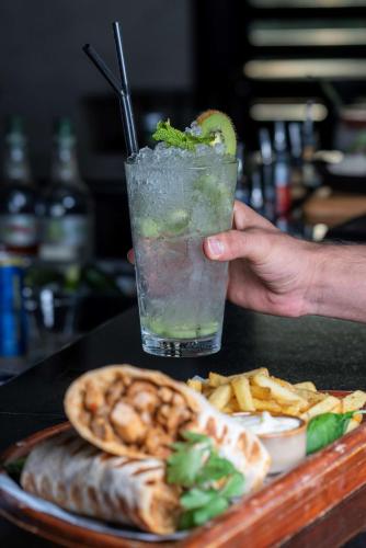 a person holding a drink with a plate of food at Radisson Blu Hotel & Resort, Sohar in Sohar