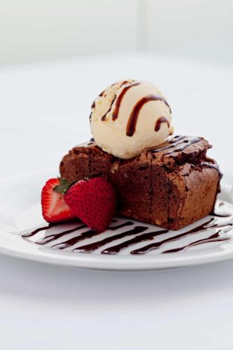 a piece of chocolate cake with ice cream and strawberries at Golden Tulip Muscat in Muscat