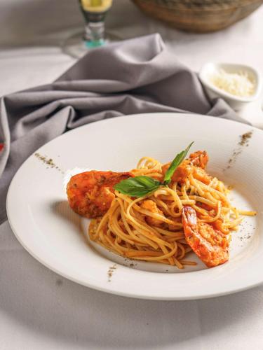 a white plate of spaghetti with meatballs and sauce at Golden Tulip Muscat in Muscat