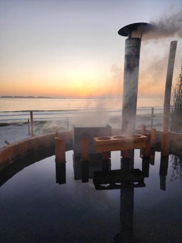 een tafel in een plas water met de zonsondergang op de achtergrond bij Refugios del Mar in Punta de Choros