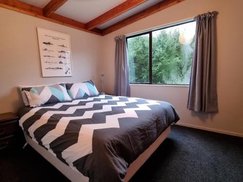 a bedroom with a large bed and a window at Treetop Treasure - Hanmer Springs Holiday Home in Hanmer Springs