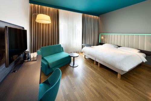 a hotel room with a bed and a tv and a chair at Park Inn by Radisson Central Tallinn in Tallinn