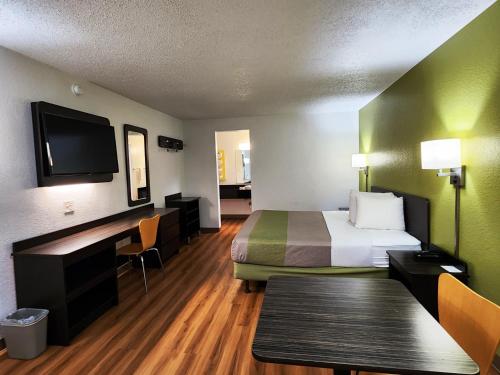 a hotel room with a bed and a desk and a tv at Motel 6-Baytown, TX - Baytown East in Baytown