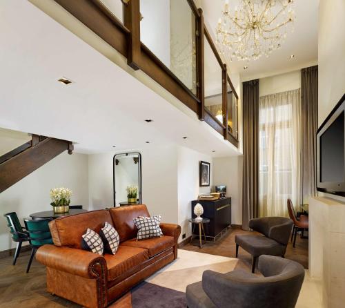sala de estar con sofá marrón y sillas en Holmes Hotel London en Londres