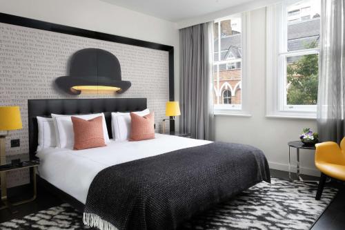 a bedroom with a large bed with a black headboard at Holmes Hotel London in London