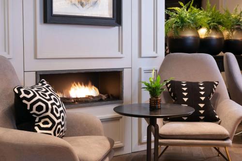 a living room with two chairs and a fireplace at Holmes Hotel London in London