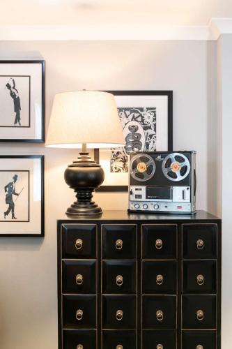 a lamp on a dresser with a radio and pictures at Holmes Hotel London in London