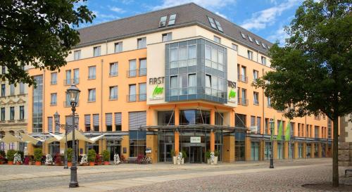 duży pomarańczowy budynek przy ulicy miejskiej w obiekcie First Inn Hotel Zwickau w mieście Zwickau