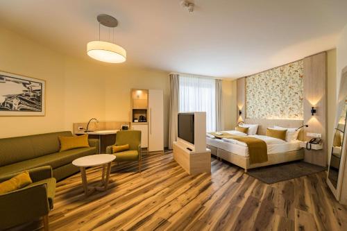 une chambre d'hôtel avec un lit et un salon dans l'établissement First Inn Hotel Zwickau, à Zwickau