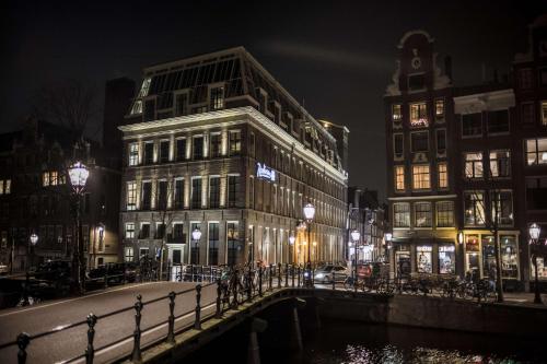 Radisson Blu Hotel, Amsterdam City Center في أمستردام: شارع المدينة بالليل فيه مباني وجسر