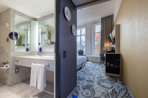 ein Badezimmer mit einem großen Waschbecken und einem großen Spiegel in der Unterkunft Radisson Blu Hotel, Amsterdam City Center in Amsterdam