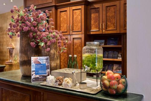 a counter with a vase of flowers and a bowl of fruit at Radisson Blu Hotel Altstadt in Salzburg