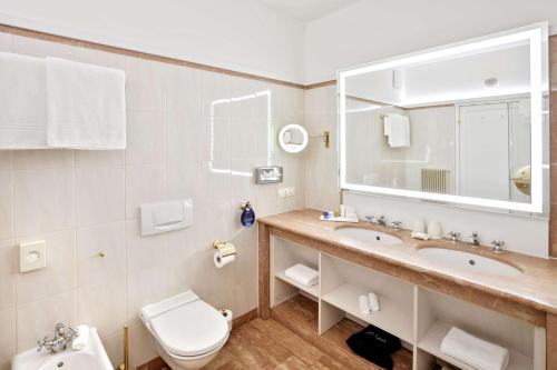a bathroom with a sink and a toilet and a mirror at Radisson Blu Hotel Altstadt in Salzburg