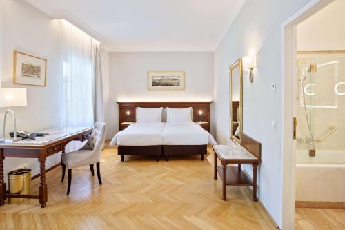 a hotel room with a bed and a desk and a bathroom at Radisson Blu Hotel Altstadt in Salzburg