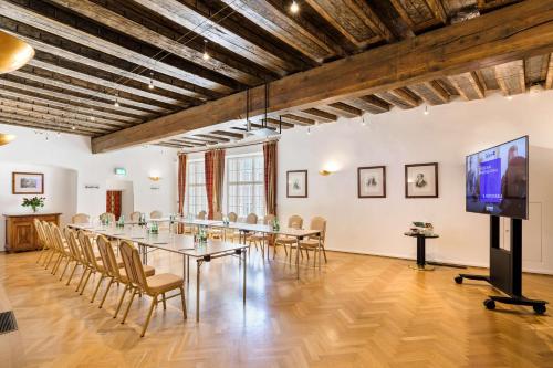 a large room with a table and chairs and a flat screen tv at Radisson Blu Hotel Altstadt in Salzburg