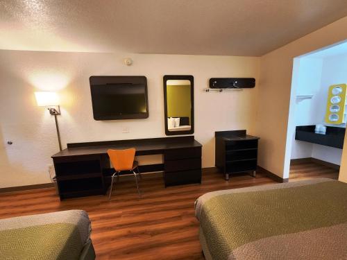 a hotel room with a bedroom with a desk and a tv at Motel 6-Baytown, TX - Baytown East in Baytown