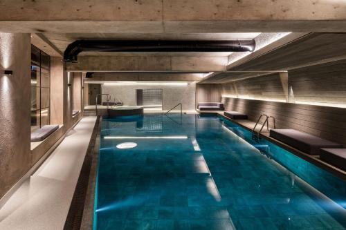 a swimming pool with blue water in a building at The Edwardian Manchester, A Radisson Collection Hotel in Manchester