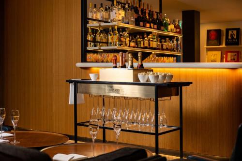 a bar with wine glasses on a shelf at The Edwardian Manchester, A Radisson Collection Hotel in Manchester