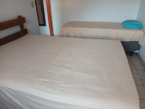 two beds in a dorm room with white sheets at ANA POIPA CANEDO in Senador Canedo
