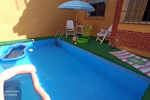 una piscina con sombrilla, mesa y sillas en Casa con piscina y barbacoa a 3 kilómetros de la Alhambra, en Huétor Vega