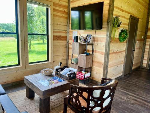 uma sala de estar com uma mesa e uma televisão na parede em Bourbon Barrel Cottages #2 of 5 on Kentucky trail em Lawrenceburg